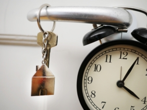 Key on doorknob in front of a clock